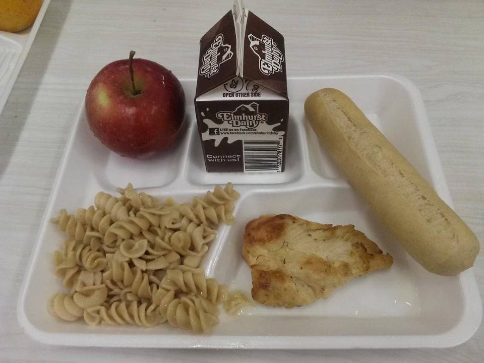 A typical school lunch. Chicken served with a side of pasta, bread and an apple with the choice of chocolate milk on a styrofoam tray. Picture taken by Keith Loh.