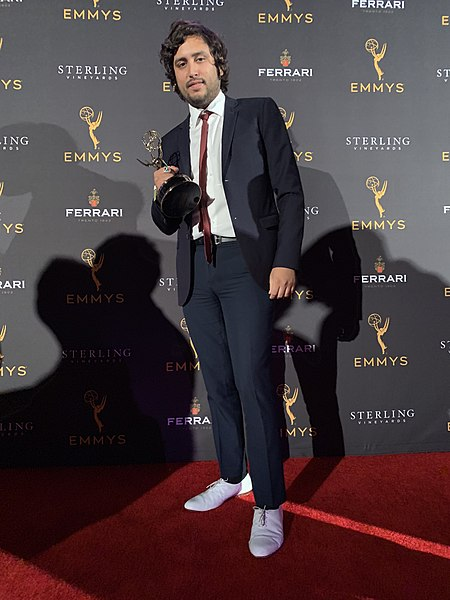 Matthew Arias holding an Emmys trophy on the Emmys red Carpet